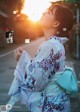 A woman in a kimono standing on the side of a road.