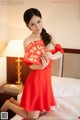 A woman in a red dress holding a red envelope.