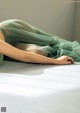 A woman laying on a bed in a green dress.