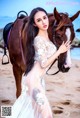 A woman in a white dress standing next to a brown horse.