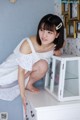 A woman in a white dress sitting on top of a dresser.