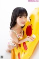 A young girl in a bathing suit playing with an inflatable toy.