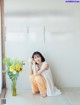 A woman sitting on the floor next to a vase of flowers.