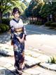 A woman in a kimono standing on a sidewalk.