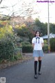 A woman in a school uniform is walking down the street.