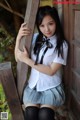 A woman in a school uniform leaning against a wooden door.