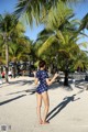 A woman in a polka dot swimsuit standing on a beach.