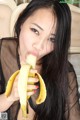 A woman holding a banana in front of her mouth.