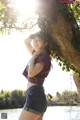 A woman leaning against a tree by the water.