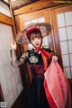 A woman in a black and red dress holding a red umbrella.