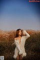 A woman in a white sweater standing in a field.