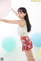 A young woman standing in front of a bunch of balloons.