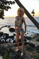 A woman standing on a rock by the ocean.