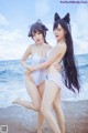 Two young women in white bathing suits on the beach.