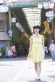 A woman in a yellow dress walking down a street.