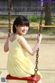 A woman in a yellow dress sitting on a swing.