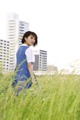 A woman in a blue dress standing in tall grass.