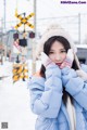 A woman in a blue jacket and hat standing in the snow.