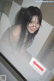 A woman wearing glasses standing in front of a mirror.