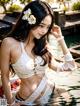 A woman in a white bikini sitting in the water.