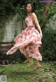 A woman in a red and white floral dress is jumping in the air.