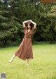 A woman in a brown dress standing in a field.