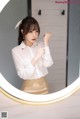 A woman standing in front of a round mirror.
