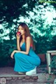 A woman in a blue dress eating an apple.