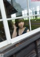 A woman looking out of a window with her hand on her head.