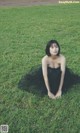 A woman in a black dress sitting on the grass.