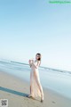 A woman standing on a beach holding a cell phone.