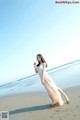 A woman in a long dress standing on a beach.