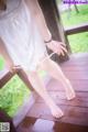 A woman in a white dress is standing on a wooden deck.