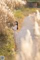 A woman standing in the middle of a dirt road.