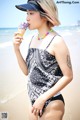 A woman in a bathing suit eating an ice cream cone.