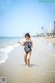 A woman in a bathing suit walking on the beach.