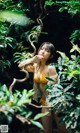 A woman in a yellow bikini holding a snake.