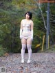 A woman in a white lingerie standing on a dirt road.