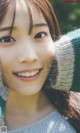 A close up of a smiling young woman wearing a sweater.