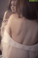A woman in a white dress looking at herself in the mirror.