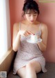 A woman sitting on a window sill eating a piece of cake.