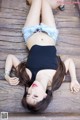 A woman laying on a wooden deck with her legs crossed.